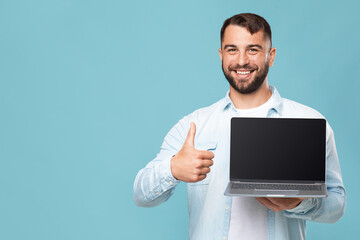 Smiling middle aged caucasian guy show laptop with empty screen and thumb up isolated on blue background