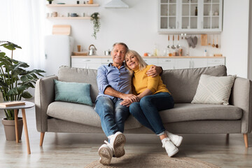 Happy Mature Couple Embracing Posing Sitting On Couch At Home