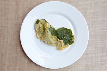 Deep fried green amaranth leaves or spinach leaves, cover with flour dough, on a white plate. Flat lay or top view.