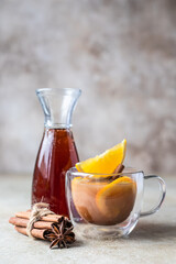 Autumn or winter hot tea or punch with orange and spices in a glass cup. Hot spicy beverage. Seasonal mulled drink.