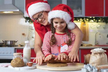 Funny Mother and daughter cooking cookies. Merry Christmas and Happy Holidays. Family preparation holiday food. Christmas baking, festive gingerbread cookies