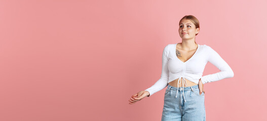 Flyer with portrait of young beautiful girl isolated on pink color studio background. Concept of human emotions