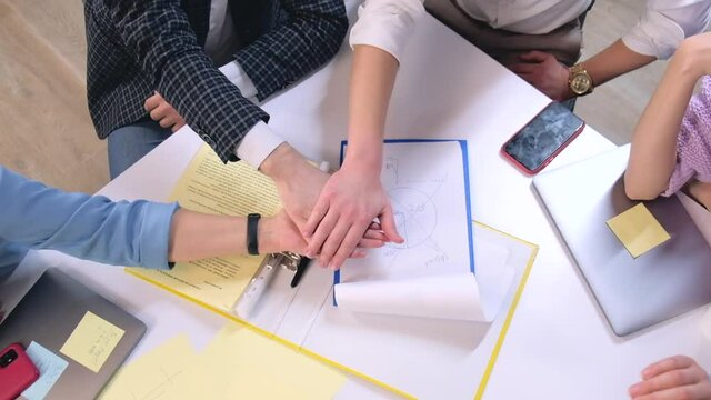 Close up footage of people in office joining hands together in slow motion.