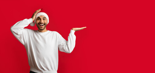 Amazing Offer. Excited Man Wearing Santa Hat Pointing Aside At Copy Space