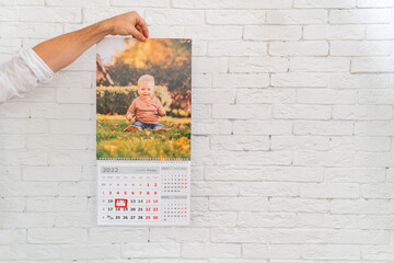 men's hand holds calendar with photo of child in front of. printed products