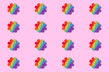 Pattern made with rainbow pop it fidget toy on pink background. Push bubble fidget sensory toy - washable and reusable stress relief toy. Antistress toy for children or adult. Mental health concept