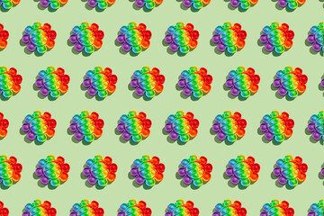 Pattern made with rainbow pop it fidget toy on green background. Push bubble fidget sensory toy - washable and reusable stress relief toy. Antistress toy for children or adult. Mental health concept