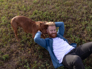 Best friends playing in the grass fields, bully dog and a young human male forming a lasting...