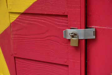 Locked padlock with chain at colorful wooden door.