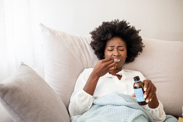Cough syrup tastes awful. Young woman making a face of disgust at a spoon full of cough syrup. Sick...