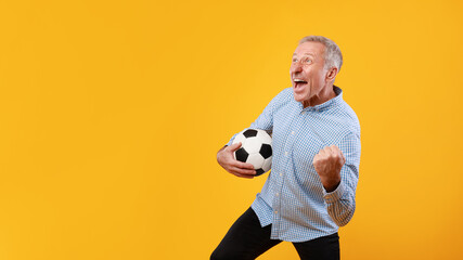 Mature man posing with soccer ball on yellow background