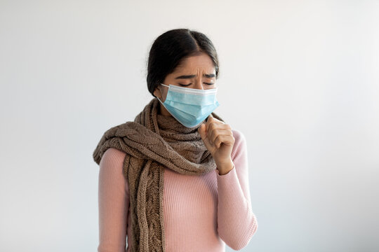 Upset Despaired Young Indian Lady In Protective Mask And Scarf Coughs, Feeling Bad And Suffers From Illness