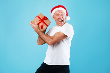 Mature Man Holding And Showing Christmas Present At Studio