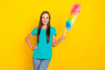 Photo of nice lady hold fluffy duster enjoy tidy work wear teal t-shirt jeans isolated yellow color background