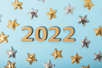 Fototapeta na wymiar Top view of the wooden numbers 2022 on blue background.Golden and silver stars around.Festive concept.