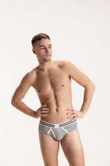 Fototapeta premium Studio shot of young handsome sportive shirtless man in underwear standing isolated on grey studio background.