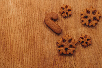 Christmas composition with handmade gingerbread cookies. Creative dessert in the form of snowflakes. Homemade sweets on a brown wooden background. Festive treats with copy space