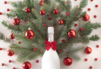 Minimal creative natural concept made of Christmas tree and white champagne with red decorative balls on light background.Christmas decoration idea. New year 2022.