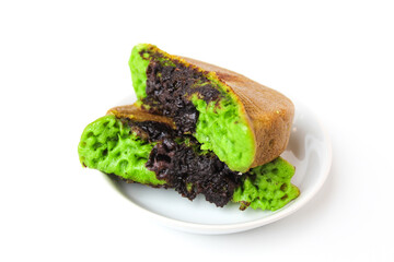 Green colored pukis with melted chocolate topping. Pukis is an Indonesian traditional sweet pancake. On a small white plate. Isolated on white background