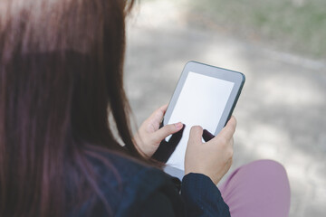 business woman wearing face mask using smartphone tablet typing on screen working with app devices in park with sunrise and blur nature background. business new normal with corona virus or covid-19.