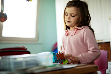 Adorable girl playing with toys at home. Little child playing with lots of toys indoor.