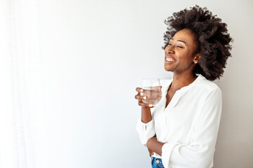 Portrait of happy smiling young woman with glass of fresh water. Healthy lifestyle concept. Young...