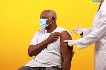Immunization and health care. Senior black male patient in face mask receiving covid-19 vaccine...