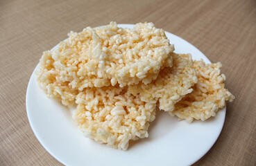 Rengginang, traditional crackers from Indonesia, made from sticky rice which dried then fried. On a white plate.
