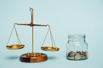 bronze justice scales near glass jar with coins on blue background, anti-corruption concept