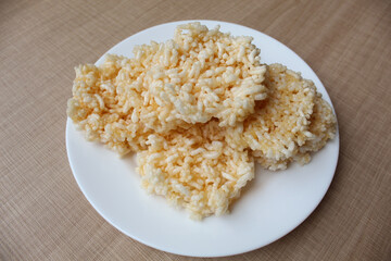 Rengginang, traditional crackers from Indonesia, made from sticky rice which dried then fried. On a white plate.