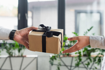 cropped view of businessman giving gift box to woman in office, anti-corruption concept
