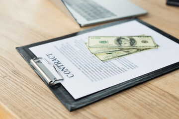 Obraz premium dollar banknotes on contract near blurred laptop, anti-corruption concept