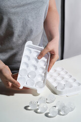 Cropped shot of men's hands holding a part of an ice tray. The ice tray with ice balls is lying on...