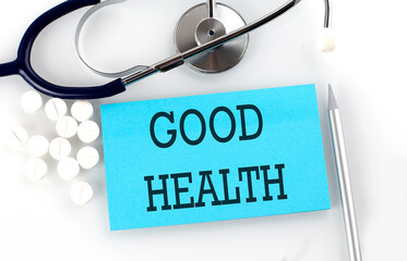 Text GOOD HEALTH on a table with a stethoscope,pills and pen, medical concept.