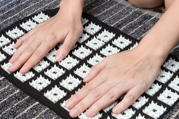 Massage of female hands on an acupuncture mat. Acupressure treatment. Alternative medicine concept