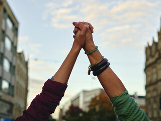 Two women holding hands up in air - obrazy, fototapety, plakaty