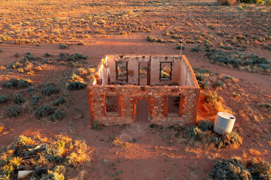 Aerial view of a brick shell of an old farmhouse amongst desert scrub