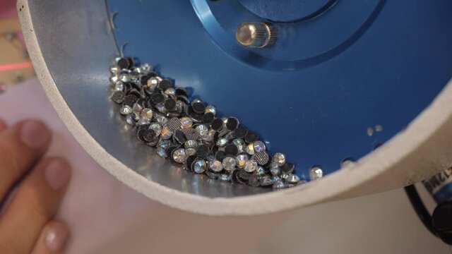 The process of applying rhinestones to clothes using an industrial machine.