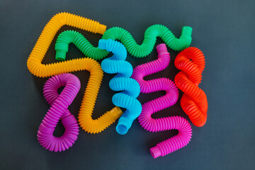 Colorful anti-stress fidget pop tube sensory toy on grey background. Flat lay.