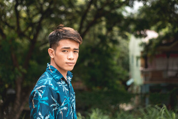 A handsome Filipino man in a casual tropical polo shirt. Copy space on right side of photo.
