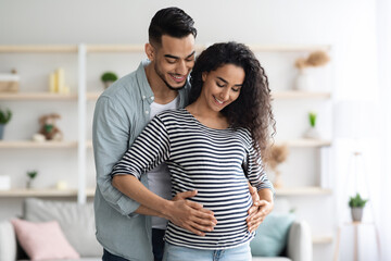 Loving middle eastern husband hugging his beautiful pregnant wife