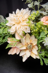 Plastic handmade bouquet artificial flowers composition.Beautiful flowers in vase on a table with black  background. Women's, mother's day. Spring, summer season. Front view.Selective focus.
