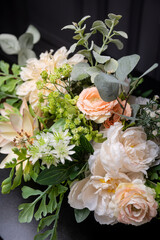 Plastic handmade bouquet artificial flowers composition.Beautiful flowers in vase on a table with black  background. Women's, mother's day. Spring, summer season. Front view.Selective focus.

