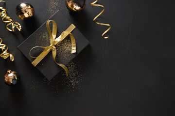 Gold and black gift and baubles on a black background with Christmas decorations. View from above....