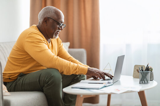 Side-View Of Mature Black Man Typing On Laptop At Home