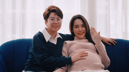 Pregnant Asian lesbian woman and her partner are happy to spend time together at home.