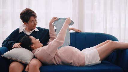 Fototapeta na wymiar Pregnant Asian lesbian woman and her partner are happy to spend time together at home.