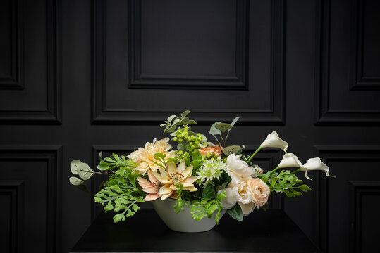 Plastic handmade bouquet artificial flowers composition.Beautiful flowers in vase on a table with black  background. Women's, mother's day. Spring, summer season. Front view.Selective focus.
