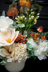 Plastic handmade bouquet artificial flowers composition.Beautiful flowers in vase on a table with black  background. Women's, mother's day. Spring, summer season. Front view.Selective focus.
