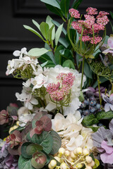 Plastic handmade bouquet artificial flowers composition.Beautiful flowers in vase on a table with black  background. Women's, mother's day. Spring, summer season. Front view.Selective focus.
